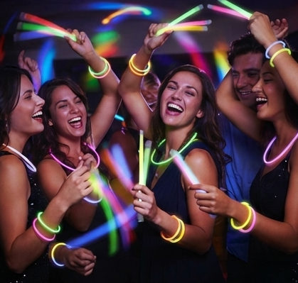 Friends laughing while waving colorful glowing glow sticks.