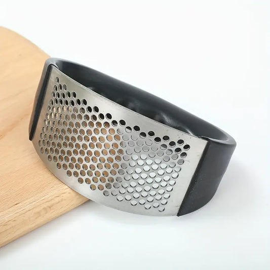Black manual garlic press with stainless perforated grating plate, side view