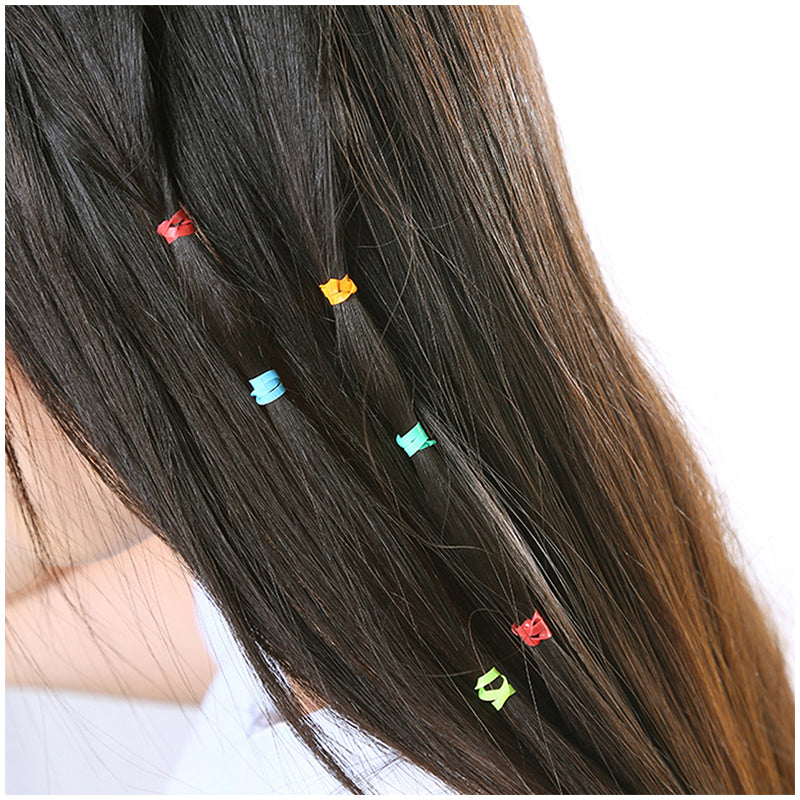 Colorful small hair elastics on dark hair with ponytail holders