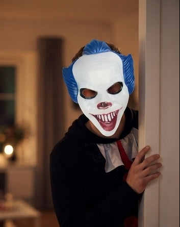 Creepy clown face mask with blue wig, white face, red teeth, worn with black costume