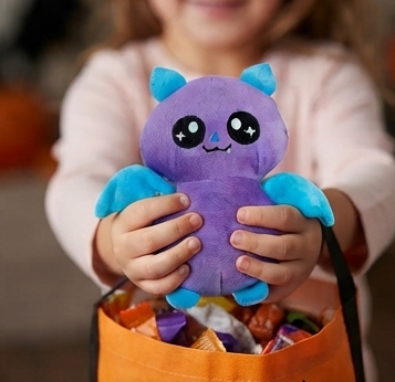 Purple bat plush stuffed animal with cute face and blue wings, held by a child