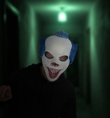 Creepy clown face mask with blue wig, white face, red grin, hollow eye openings
