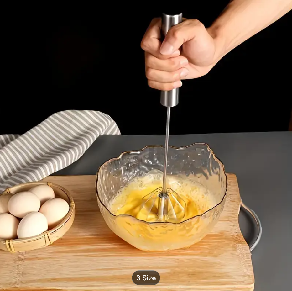 Stainless steel milk frother whisk held above a bowl with spring wire head
