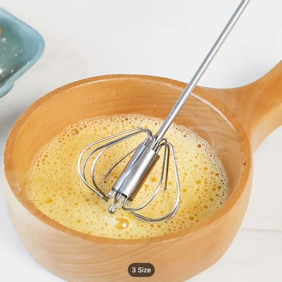 Stainless steel whisk beater with spring loops stirring foam in a mixing bowl
