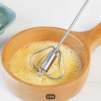 Stainless steel whisk beater with spring loops stirring foam in a mixing bowl