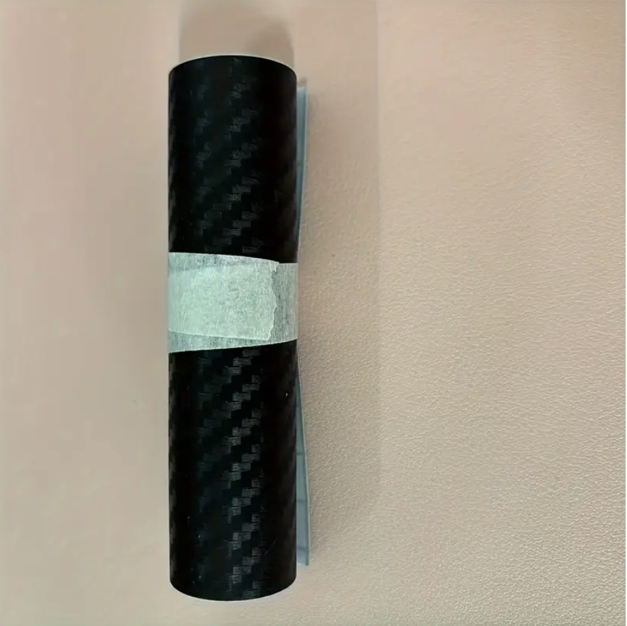 Rolled dark carbon fiber protection film on a white backing with release liner