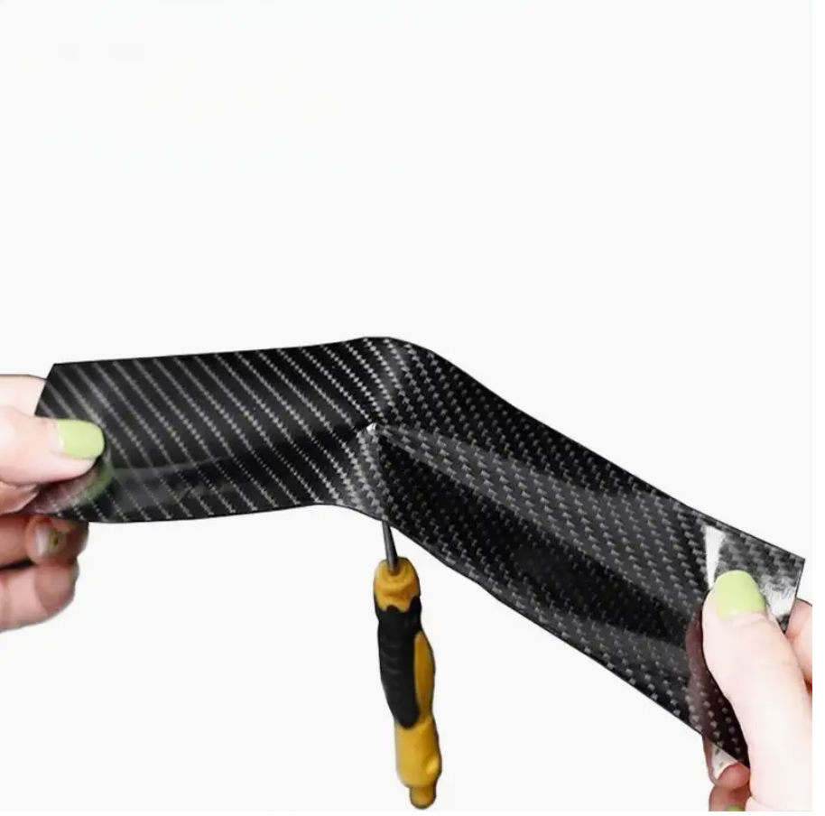 Hands trimming dark carbon fiber protection film strip for a curved surface