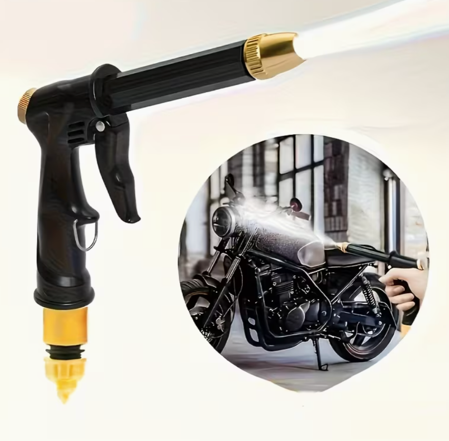 Black pressure washer spray gun with brass tip, water mist aimed at an engine.