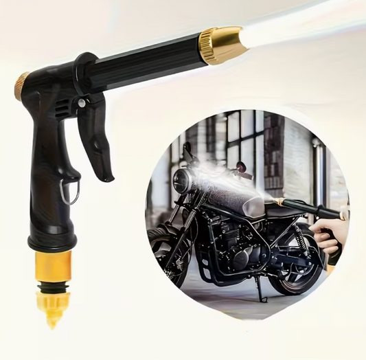 Black pressure washer spray gun with brass tip, water mist aimed at an engine.