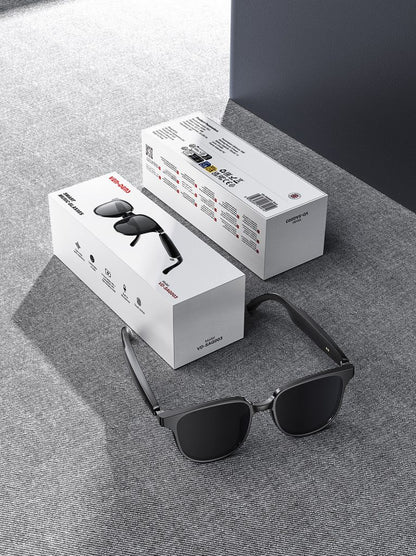 Black aviator Bluetooth audio sunglasses with open-ear design shown with product boxes