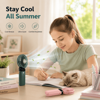 Pink and green mini handheld fans on a desk beside a notebook and small plant