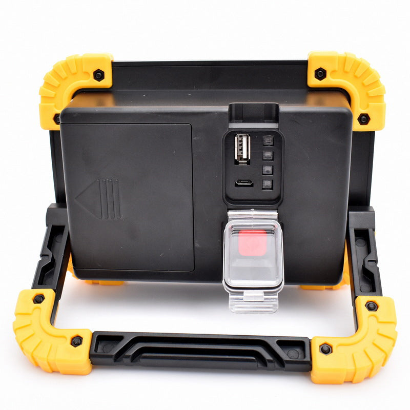 Rear panel of portable COB work light, black with yellow sides, USB ports and charging dock