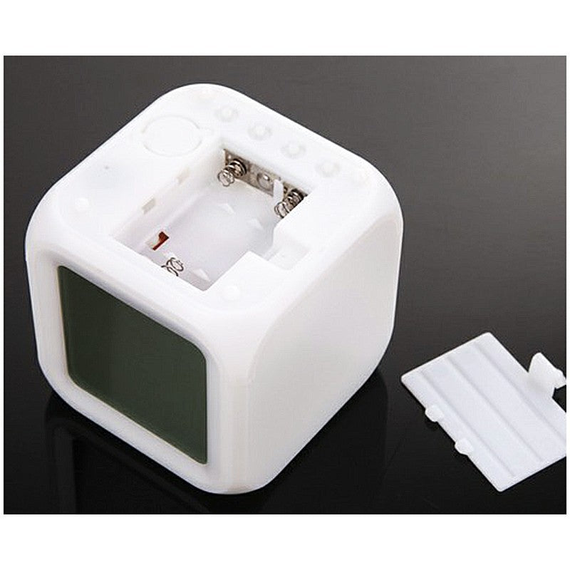 White cube alarm clock with open battery compartment and visible battery space