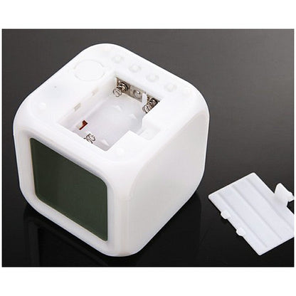 White cube alarm clock with open battery compartment and visible battery space