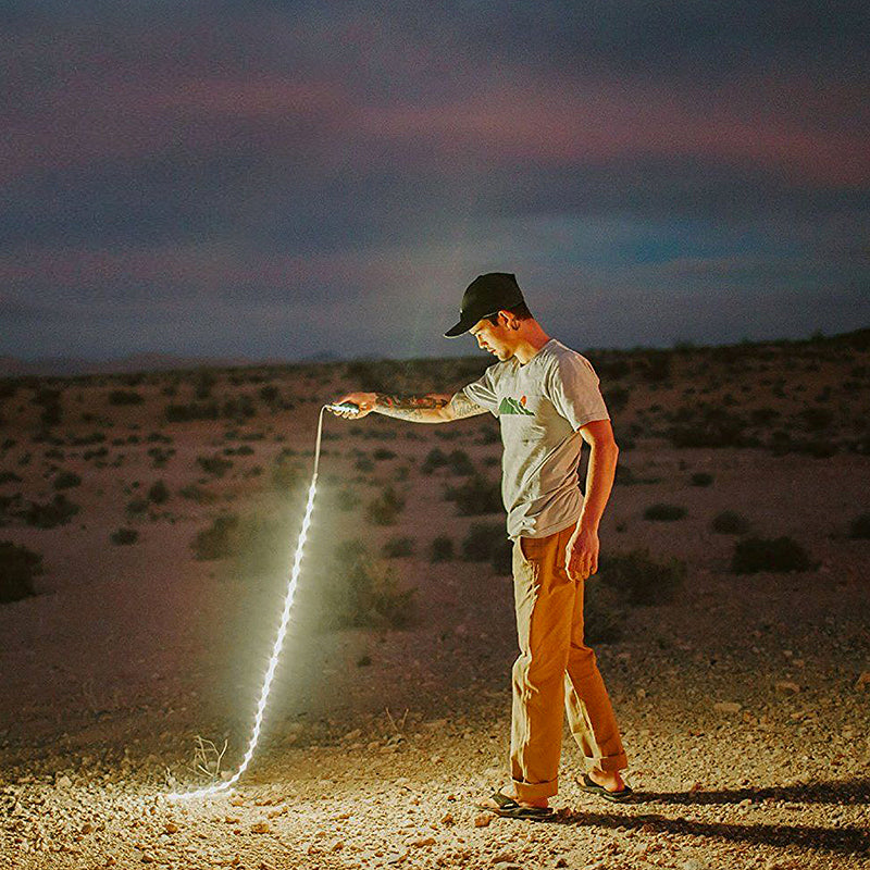 Person using an RGB LED strip outdoors, emitting a bright line of light