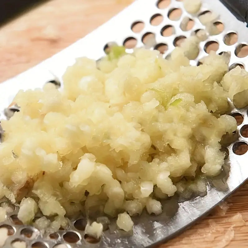 Close-up of minced garlic filling the stainless perforated grating plate
