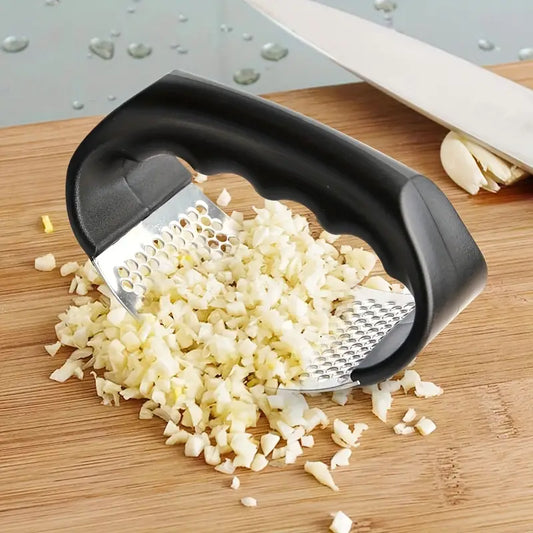 Black manual garlic press with stainless perforated plate over chopped garlic