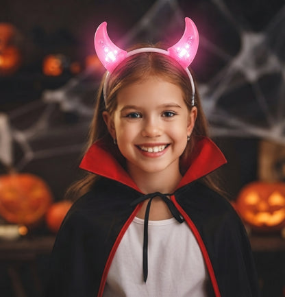 Glow headband with pink lit devil horns worn by a smiling child