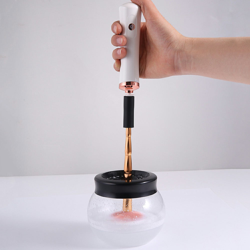 White handheld brush cleaner dryer with copper nozzle over clear bowl