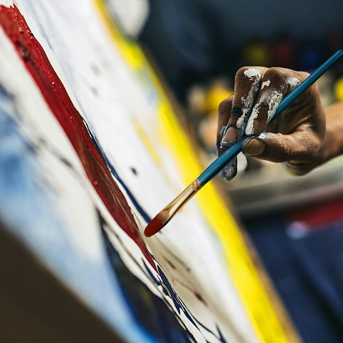 Face painter applying paint with a blue-handled brush with orange tip