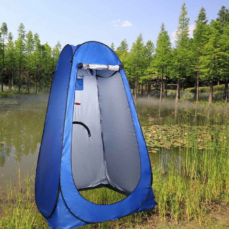 Blue pop-up shower changing tent with open front privacy panel outdoors near a pond