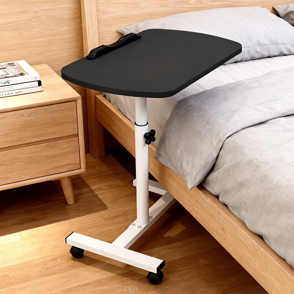 Adjustable overbed table with black tray top and white height-adjustable legs