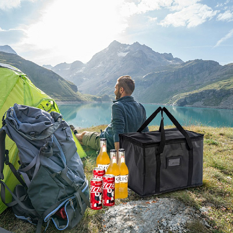 Black insulated delivery bag with bottles on a grassy outdoor setting