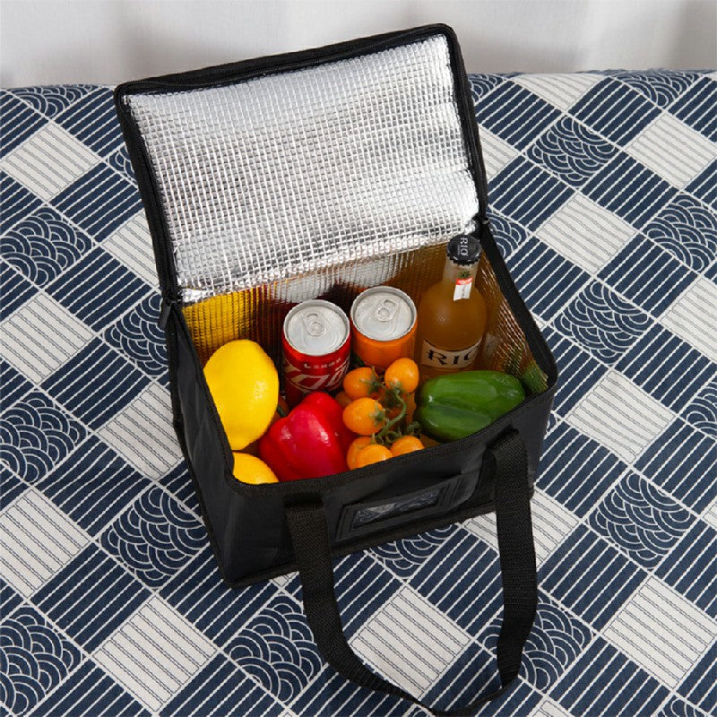 Black insulated bag open with silver lining and assorted groceries inside