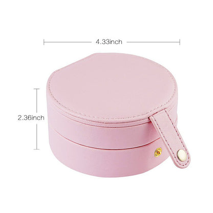 Pink round PU leather jewelry case with top lid, side strap, and gold clasp
