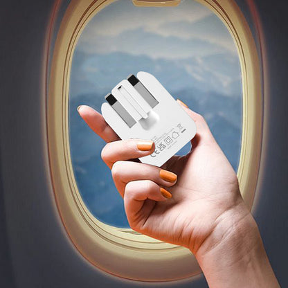 White foldable USB-C mains adapter in hand with prongs folded for travel