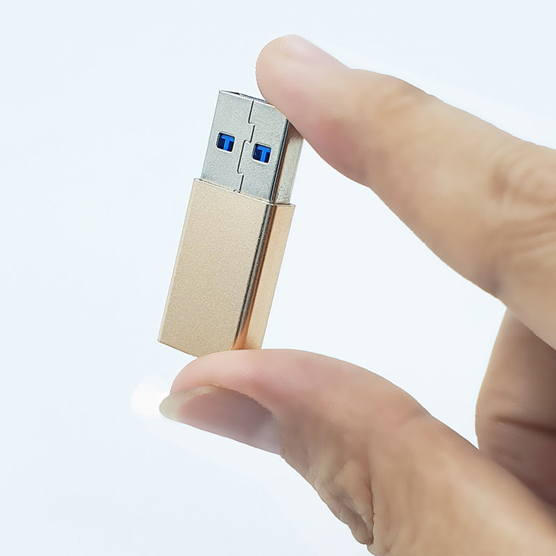 Gold USB-A male to USB-C female adapter with thumb close-up
