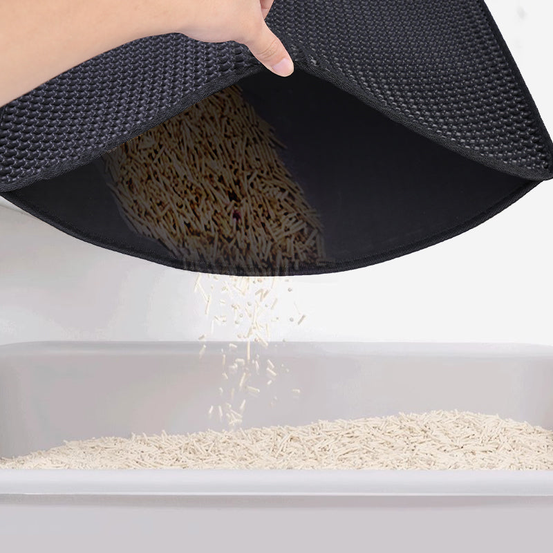 Folded black cat litter mat showing sand trapped inside the inner layer