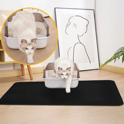Black cat litter mat with raised texture, cat at the edge of a litter box