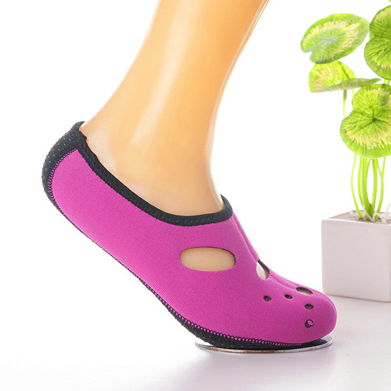 Rose red slip-on water socks on foot with black rim and oval ventilation holes