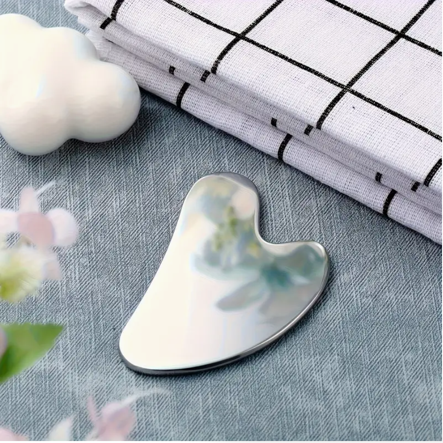 Stainless steel gua sha facial massager double-head tool on fabric