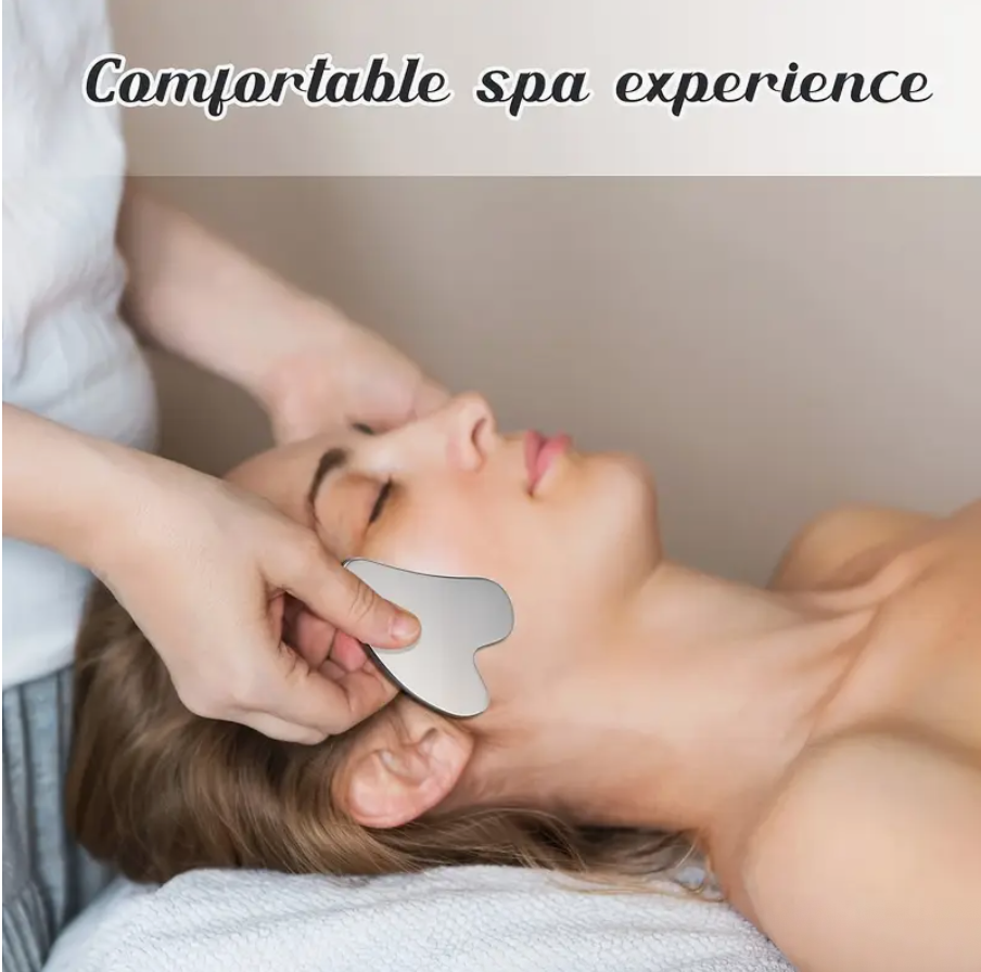 Stainless steel gua sha facial massager tool held at the under-eye area during use